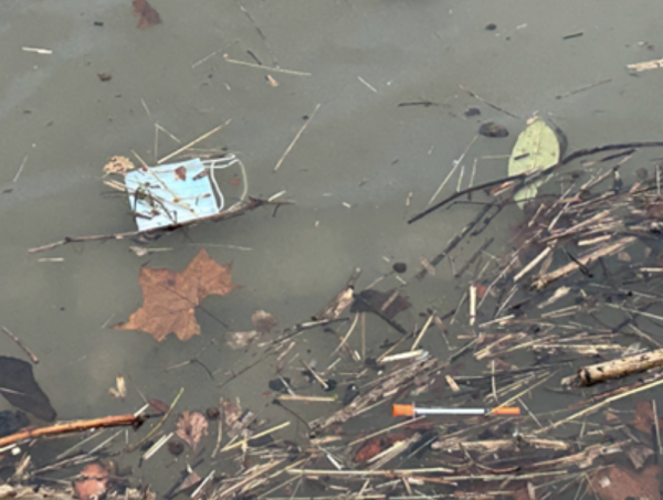A mask, needle and other trash floats in the Mon River last week.